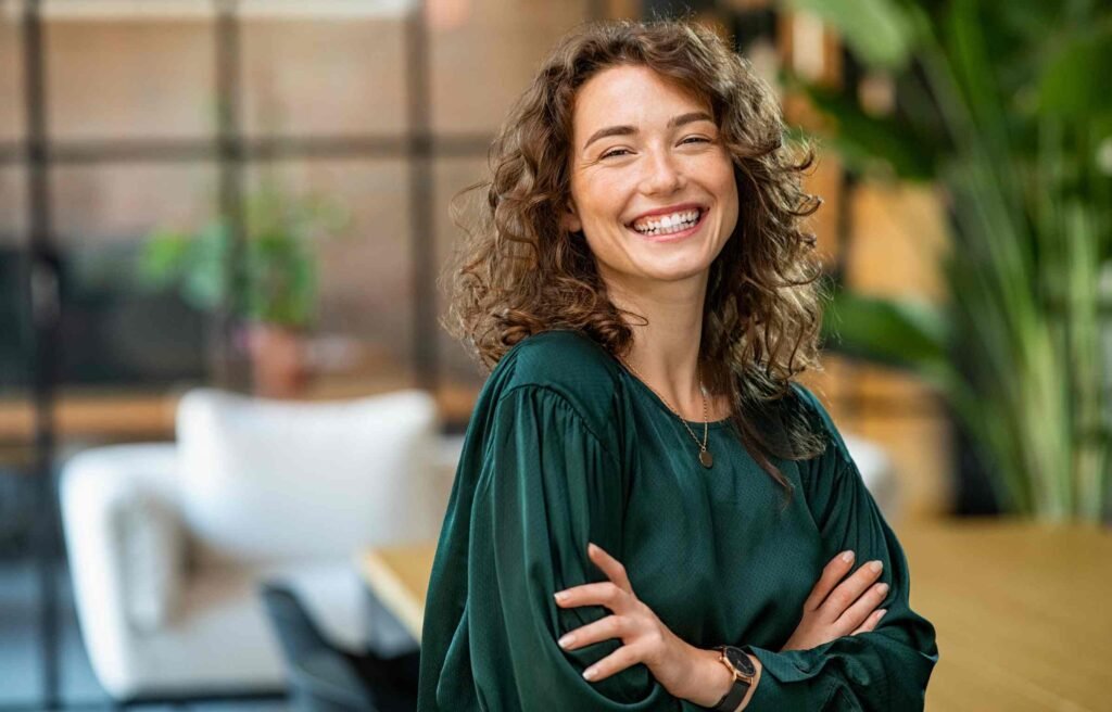 A smiling woman wearing a green t-shirt enjoys "funny jokes for girlfriend to make her laugh."