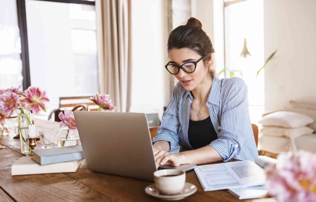 A woman working remotely on a laptop at home, representing modern types of remote jobs.